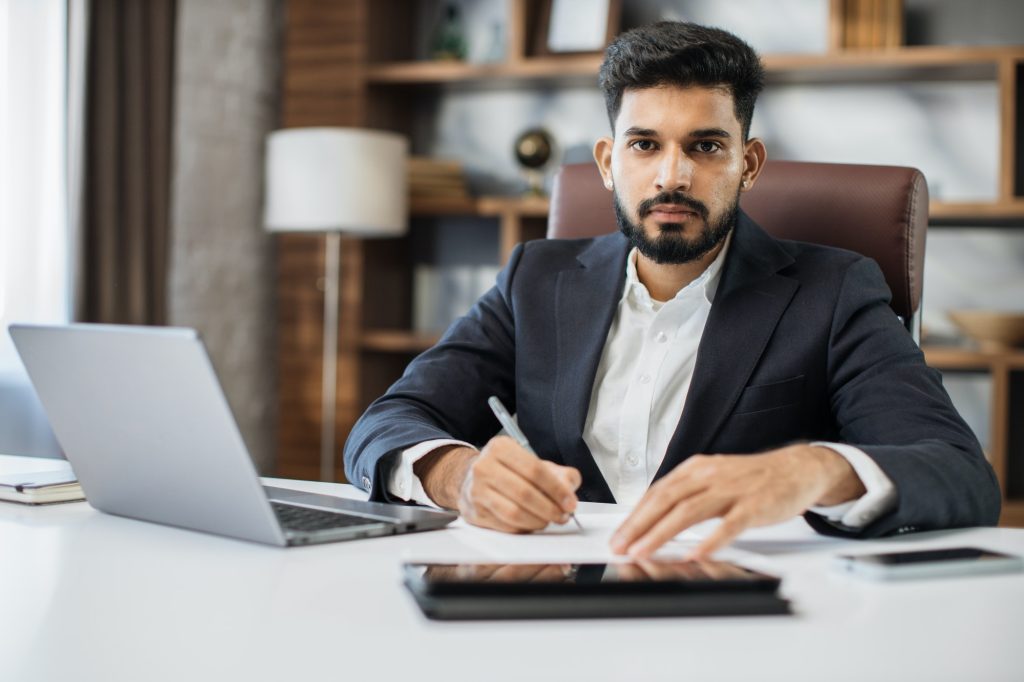 Young bearded male accountant working from modern office using laptop